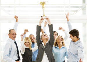 Successful businesspeople celebrating with the cup in hands.